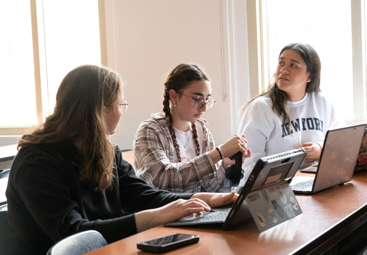 trois étudiants assis côte à côte travaillant sur des ordinateurs portables